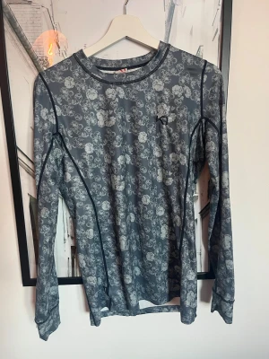 Grå/blå underställströja från Kari Traa - Snygg långärmad underställströja från Kari Traa i grått/blått med blommigt mönster och mörkblå sömmar. Perfekt för träning eller som lager under kalla dagar. Använd endast fåtal gånger, strl M, mycket bra skick!🩵🩵