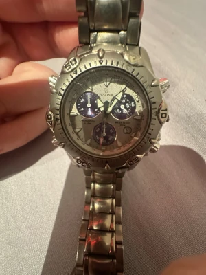Festina silverfärgad kronografklocka - Stilren kronografklocka från Festina i silverfärgat metallarmband och boett. Urtavlan har flera mindre visare för tidtagning och alarm, samt datumvisning. Vattentät upp till 100 meter. Perfekt accessoar för dig som gillar sportig och klassisk stil. Funkar ej 