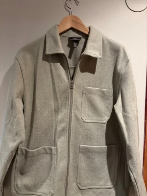 Overshirt h&m - Overshirt i ljusgrön fleece med tre stora utanpåliggande fickor och dragkedja framtill. Rak passform och klassisk krage, perfekt för lager på lager. Enkel och stilren design som funkar till det mesta.