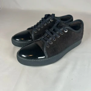 Helsvarta Lanvins - Snygga svarta Lanvins med ovandel i mjuk mocka och glansig lackdetalj på tån. Skorna är i bra skick och är storlek 7uk vilket motsvarar 41-42 i Lanvin storlek.  Perfekta för dig som gillar en stilren look.