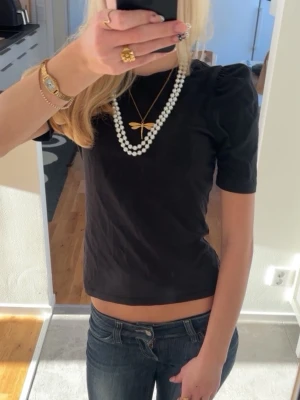 Svart topp med puffärm - Säljer en svart  topp med puffiga axlar och korta ärmar. Toppen har en enkel, stilren design och sitter tight mot kroppen. Perfekt att matcha med jeans eller kjol för en trendig look.