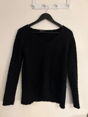 Dam Svart fluffig stickad tröja - Mysig svart fluff tröja från Gina Tricot med fluffig textur och v-ringad hals. Långärmad modell som är perfekt för kyligare dagar. Enkel och stilren design som passar till allt. I storlek XS och använd en gång.