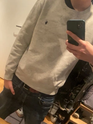 Grå tröja från Polo Ralph Lauren  - Klassisk grå sweatshirt från Polo Ralph Lauren i storlek S. Tröjan har rund halsringning, ribbade muddar och den ikoniska broderade loggan på bröstet. Tillverkad i mjuk bomull för skön känsla och perfekt för våren och sköna kvällar. #grisch #ralphlauren #poloralphlauren 