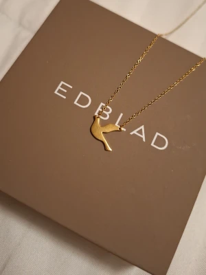 Halsband - Bilderna visar ett halsband från Edblad med en guldfärgad duva som berlock, men ingen väst finns med. Nypris:300 säljer för fick 2 likadana i prisent