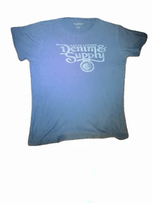 Grå  t-shirt från Ralph Lauren - Snygg gråt-shirt från Ralph Lauren Denim & Supply med stort tryck. Tillverkad i 100% bomull. Strl L och i mycket bra skick! Exlusive t shirt då dem ej tillverkas mer!