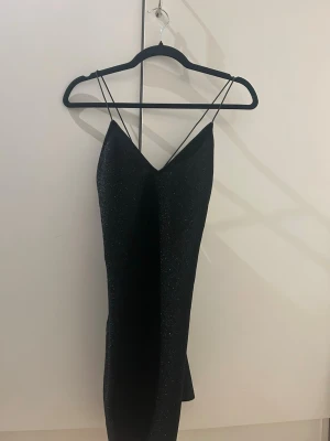 Glittrig svart klänning med smala band - Kort svart glittrig klänning. Oanvänd med prislapp kvar. Nypris 129kr