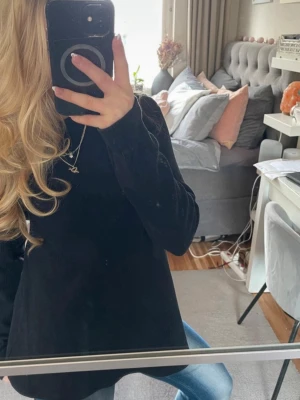 Svart ribbad topp från Hanro - Säljer en svart långärmad topp från Hanro i ribbad bomull. Toppen har en högre rundad halsringning och sitter snyggt med en lätt utsvängd passform. Perfekt att styla med jeans eller kjol för en clean look.