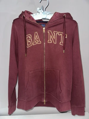 Gant zip-hoodie  - Vinröd Gant zip-hoodie med guld tryck i stl. S