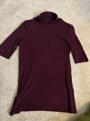 Vinröd polotopp från Pieces - Säljer en vinröd polotopp från Pieces i storlek S. Toppen har halvlånga ärmar och en hög polokrage. Materialet är mjukt och stretchigt, vilket gör den riktigt skön att bära. Perfekt att styla med jeans eller kjol för en clean look.