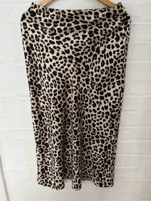 Leopardmönstrad långkjol från Zara - Säljer en snygg långkjol från Zara i leopardmönster. Kjolen har beige botten med svarta och bruna fläckar och är i ett mjukt, följsamt material. Perfekt för dig som vill sticka ut och älskar djurmönster.