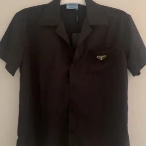 Prada Skjorta  - Kortärmad skjorta från Prada.                             Storlek M.                                                                          Använd några få gånger men har ej något tecken på användning, som nytt skick.                                         