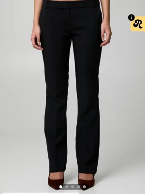 Svarta kostymbyxor  - Snygga svarta kostymbyxor lågmidjade, perfekta för en clean och stilren look. Passar dig som gillar enkel design och vill ha ett par byxor som funkar till många olika outfits.