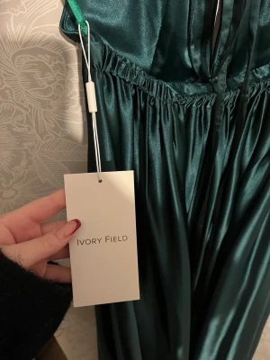 Balklänning  - Jättefin balklänning – stk 2 (oanvänd) Superfin smaragdgrön balklänning från Ivory Field i storlek 2/xs på hemsidan men skulle säga att den sitter mer som en S. Oanvänd med lapp kvar och i perfekt skick. Djup ringning, halterneck, öppen rygg med korsade band samt slits som ger en fin form. Perfekt till bal, bröllop eller gala. Nypris: 2500 kr. 