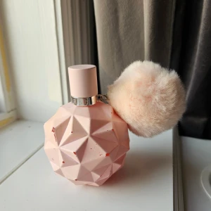 Ariana Grande Sweet Like Candy parfym - Säljer en Ariana Grande Sweet Like Candy parfym i en ljusrosa, geometrisk flaska med en fluffig rosa boll som dekoration. Flaskan rymmer 100 ml och går inte att se igenom hur mycket som är kvar men gissar på runt hälften, flaskan är sliten men parfymen är bra🙂
