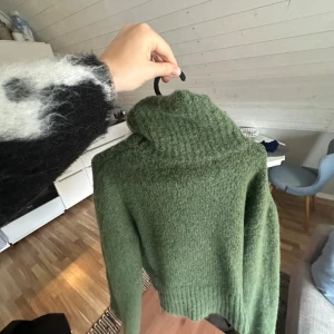 Grön stickad polotröja från Zara - Mysig grön stickad polotröja från Zara i storlek M. Tröjan har en hög polokrage, lång ärm och är tillverkad i ett fluffigt, stickat material som känns både trendigt och bekvämt. Perfekt för lager-på-lager och chill dagar.