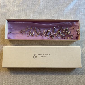 Pärlhalsband från Oskar Persson - Unikt halsband med pärlor i olika storlekar och färger som vit, grå, brun och guld. Pärlorna är fästa på tunna trådar vilket ger ett luftigt och elegant uttryck. Pris kan diskuteras. 