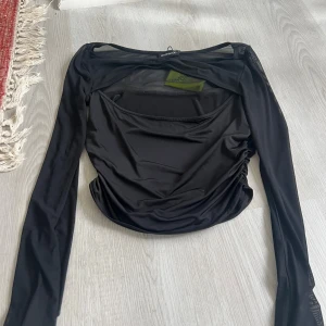 Svart mesh topp från Even&Odd M - Svart långärmad topp från Even&Odd i mesh och polyester. Toppen har transparenta partier upptill och på ärmarna, samt rynkade sidor för en snygg passform. Perfekt för dig som gillar trendiga detaljer och en edgy look.