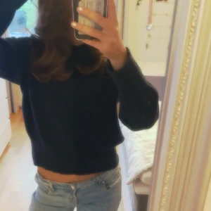 Mörkblå stickad croppad tröja - Mysig mörkblå stickad tröja med långa ärmar. Perfekt för dig som gillar en enkel men snygg look. Tröjan har en klassisk rund halsringning och är superenkel att matcha med jeans eller kjol.