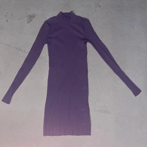 Lila ribbad långärmad klänning H&M - Säljer en tight, ribbad lila klänning från H&M i storlek XS. Klänningen har lång ärm, hög krage och är i stretchigt material som sitter snyggt på kroppen. Perfekt för dig som gillar en enkel men stilren look.
