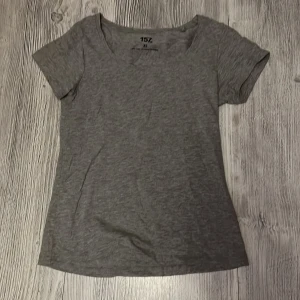 Grå basic t-shirt från 157, XS - Enkel grå t-shirt från 157 i storlek XS. T-shirten har rund halsringning och korta ärmar. Tillverkad i mjuk bomullsblandning som känns skön mot huden. Perfekt till jeans eller shorts för en clean look.