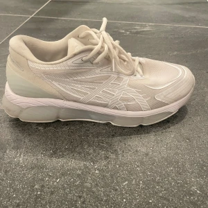 Vita Asics Gel Quantum 360 sneakers - Säljer ett par fräscha Asics Gel Quantum 360 sneakers i helvitt. Skorna har en chunky sula, mesh- och syntetmaterial, samt Asics ikoniska logga på sidorna. Perfekta för dig som gillar sportig stil och vill ha bekväma skor med snygg design.