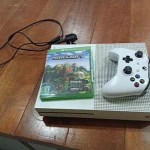 Xbox One S - Xbox One S i fint skick med original vit handkontroll och strömkabel. Minecraft-spel ingår. Konsolen och kontrollen ser välvårdade ut utan synligt slitage eller repor. Perfekt för familjespel och underhållning.