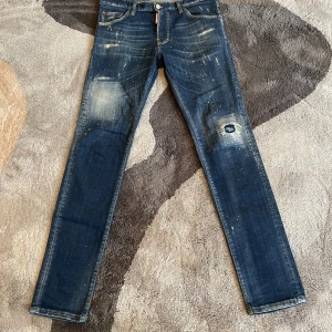 Dsquared2 cool Guy jeans - Äkta jeans från Dsquared2 med slitningar och färgstänk framtill samt klassisk femficksmodell och snyggt slitna detaljer. Använd ett fåtal gånger. 