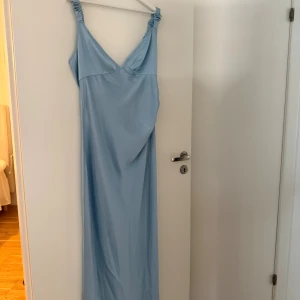 Adoore- Nimes slip dress - Supersnygg ljusblå långklänning från Adoore med smickrande v-ringning och rynkade axelband. Klänningen har en mjukt glansig yta och är tillverkad i ett satin material som faller fint. Perfekt för dig som vill ha en elegant och stilren look. Den är aldrig använd men lappen är tyvärr borta. Hör av dig vid intresse🌸🌟🙌🏼