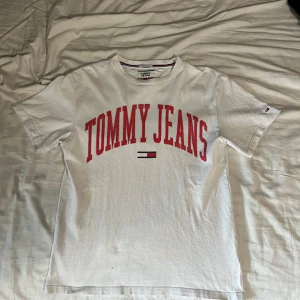 Tommy Hilfiger - Vit vintage t-shirt ifrån Tommy Jeans. Lätt använd, med enbart en liten defekt på framsidan som syns på sista bilden.  Storlek: S men funkar till M  Hör gärna av dig för fler bilder eller svar på frågor.