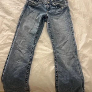 Ljusblå jeans från Gina Tricot - Snygga ljusblå jeans från Gina Tricot med klassisk femficksdesign och raka ben. Jeansen har normalhög midja och är tillverkade i mjukt bomullsjeansmaterial. Bakfickorna har lock och knappdetaljer som ger en cool touch.