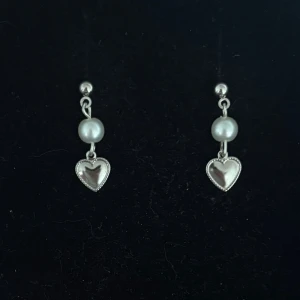 Silverörhängen med pärla och hjärta - Handgjorda och unika silverörhängen 🤩 Öronhängerna är nickelfria och silverpläterade i kirurgiskt stål, resterande av örhänget är i rostfritt stål (ej silverpläterat) 💕🙏 2 cm långa. Alla köp görs via ”KÖP NU” knappen.  💐