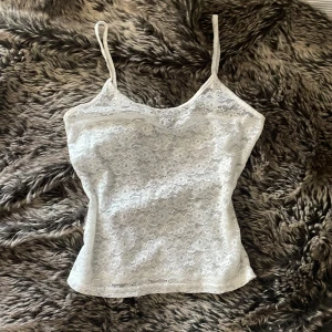 Vit spetsig linnetopp från SHEIN - Säljer en vit linnetopp från SHEIN i storlek S. Toppen är helt täckt av blommig spets och har smala axelband. Den är figurnära och har en feminin v-ringad form. Perfekt för dig som gillar romantiska detaljer och vill ha en lätt och luftig topp.