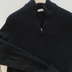 Svart stickad half zip-tröja These Glory Days - Svart stickad tröja från These Glory Days i storlek L. Tröjan har en hög krage och en snygg half zip-dragkedja med rund detalj. Ribbstickad struktur och långärmad modell, perfekt för kyliga dagar.