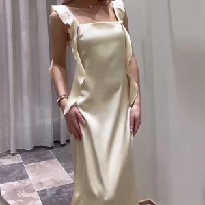 Ljusgul långklänning med volang - Elegant långklänning i ljusgult satin från veromoda. Säljer då den tyvärr var för lång för mig (helt ny och aldrig använd)