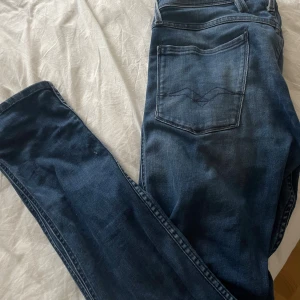 Replay Anbass jeans blå denim - Snygga blå jeans från Replay, modell Anbass. Klassisk femficksdesign med Replay-logga på fickan och bakficka med broderad detalj. Jeansen har en smal passform och är tillverkade i mjuk denim med lite stretch för extra komfort.