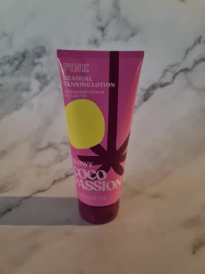 PINK Glowy Coco Passion Tanning Lotion - Gradual tanning lotion med passionfruktextrakt och sheasmör. Kommer i en rosa tub med gul och mörklila design, 200 ml. Ger en naturlig solkysst look och är vegansk samt fri från artificiella färgämnen. Doftar tropiskt och återfuktar huden. Helt ny och oanvänd