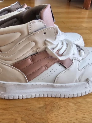 Juicy Couture vita /rosa high top sneakers - Säljer ett par high top sneakers från Juicy Couture i vitt och ljusrosa. Skorna har tjock vit sula, snörning med metall-detaljer och präglad Juicy-logga bak och under sulan. Perfekta för dig som vill sticka ut med en retro vibe. Används bara 2 gånger,  som nya ! Priset kan diskuteras! Finns ej köpa någonstans 