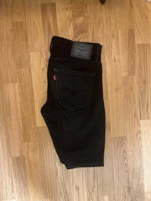 Levi's 512 slim fit - Säljer ett par svarta Levi's 512 jeans med klassisk femficksdesign och smal passform. Jeansen har en diskret svart tvätt, Levi's patch bak och röda logotag på bakfickan. Perfekta för dig som gillar en clean och stilren look.