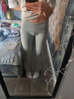 Gråa mjukisbyxor med låg midja - Säljer ett par ljusgrå mjukisbyxor med bred, låg midja och tight passform. Byxorna är raka i benen och gjorda i mjukt bomullsmaterial, perfekta för chill dagar hemma eller när du vill vara bekväm men ändå se snygg ut.