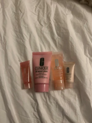 Clinique ansiktsvård mini-kit - Säljer ett set med fyra små ansiktsprodukter från Clinique. Innehåller en rosa foaming cleanser, två olika gelbaserade fuktkrämer och en ansiktsmask. Alla produkter kommer i praktiska tuber i rosa och beige toner, perfekta för resan eller att testa nya favoriter.