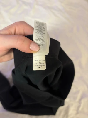 Svarta leggings från Nike XS - Säljer ett par svarta leggings från Nike i storlek XS. De har en klassisk tight passform och är tillverkade i mjukt och stretchigt material. Nike-loggan sitter snyggt på ena benet. Perfekta för träning eller chill dagar.