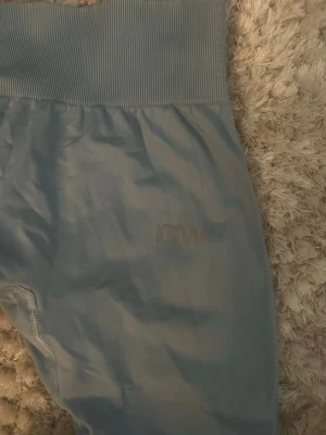 Ljusblå tights från ICANIWILL - Säljer ett par ljusblå seamless tights från ICANIWILL med hög midja och bred ribbad linning. Materialet är stretchigt och passar perfekt för träning. Diskret ICANIWILL-logga på benet. Superskön passform och snygg färg!
