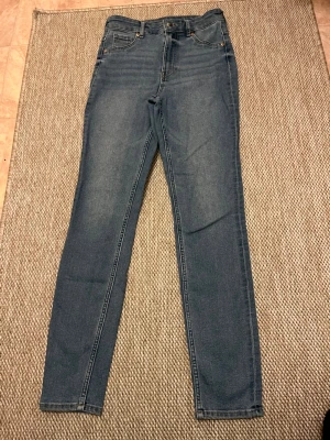 Mörkblå skinny jeans med hög midja - Säljer ett par mörkblå skinny jeans med hög midja och klassisk femficksdesign. Jeansens hela längd är 95 cm. Aldrig använt😊