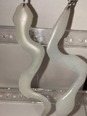 Örhängen  - Handgjorda örhängen som görs av mig. Med två vita, ormliknande berlocker. Frakten är ca 22-100kr beroende på vikten på produkten . Kontakta mig om du vill köpa.