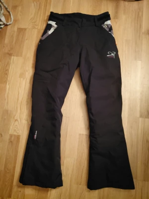 Svarta täckbyxor 2117 of Sweden S - Säljer ett par svarta täckbyxor från 2117 of Sweden i storlek S. Men passar XS då de kan ändras i midjan och är slimfit. Byxorna har coola camo-detaljer vid fickorna, bälteshällor och kardborrband i midjan. Materialet är slitstarkt och perfekt för vinterns alla äventyr. Miljövänlig ECO-modell.