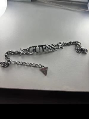GUESS silverarmband  - Trendigt GUESS-armband i silverfärg med ikonisk logotyp och stjärndetaljer. Ett stilrent statement-smycke som passar både vardag och fest. Använt fåtal gånger, i mycket fint skick.