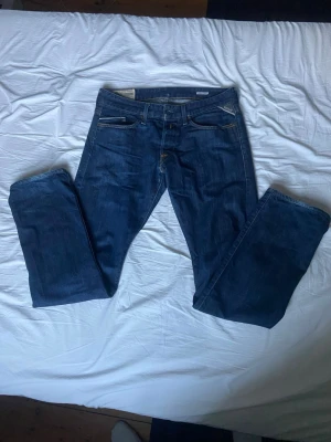 Blå Replay jeans straight fit - Säljer ett par klassiska blå jeans från Replay med raka ben och snygga kontrastsömmar. Jeansen har fem fickor, normal passform och ett läderpatch bak i midjan. Perfekta till vardagslooken och riktigt sköna att bära hela dagen.