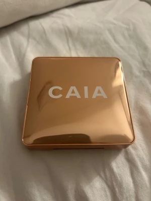 CAIA highlighter i guldig ton - Säljer en CAIA highlighter i en lyxig, guldig metallisk dosa med spegel. Pudret har en skimrande champagnefärg och är pressat i ett snyggt cirkelmönster. Perfekt för att ge glow till ansiktet och highlighta kindbenen. Köpt av en tjej på Plick för 200kr med frakt! Säljs då jag inte riktigt tyckte om highlightern på just mig och har endast använt den ca 2-3 gånger efter säljaren. Sista bild är lånad av tjejen jag köpte highlighter från!🥰Pris kan diskuteras! (Tar ej emot bud under 150kr) 