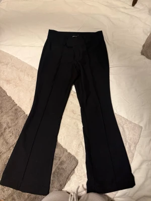 Svarta bootcut kostymbyxor Gina Tricot - Snygga svarta kostymbyxor från Gina Tricot i storlek 36. Byxorna har bootcut-modell med pressveck, hällor för bälte och fuskfickor bak. Perfekta till en clean och stilren look. Materialet känns mjukt och har en lätt stretch. Dom är nedsydda i längderna för en tjej i läng ,157-,158