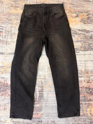 Svarta baggy jeans från House - Säljer ett par svarta baggy jeans från House i storlek 29/32. Jeansen har klassisk femficksdesign, raka ben och en avslappnad passform. Materialet är slitstark denim och färgen är tvättad svart med lätt urtvättad look.